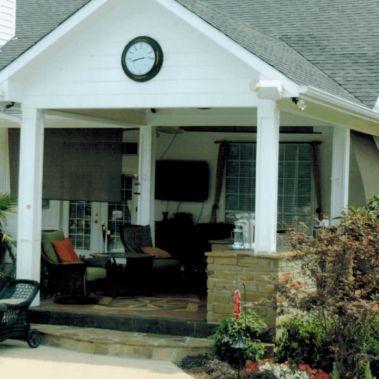 A home with a large, covered backyard porch full of patio furniture.