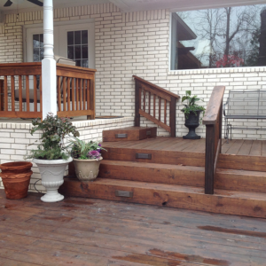 Freshly installed wooden steps and a wooden deck leading up to a home's back door.