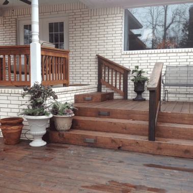 Freshly installed wooden steps and a wooden deck leading up to a home's back door.