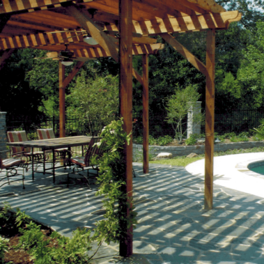 An intricate wooden backyard patio covering a table next to a pool.