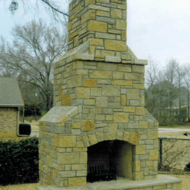 A large stone chimney in a back yard.