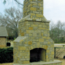 A large stone chimney in a back yard.