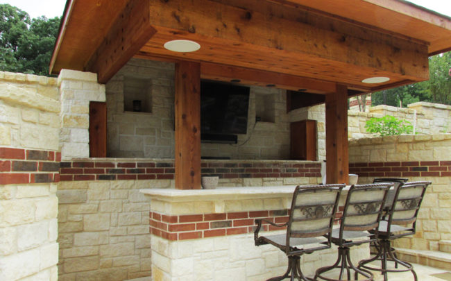 bar A backyard bar covered with a large wood overhang, with chairs facing a mounted TV.